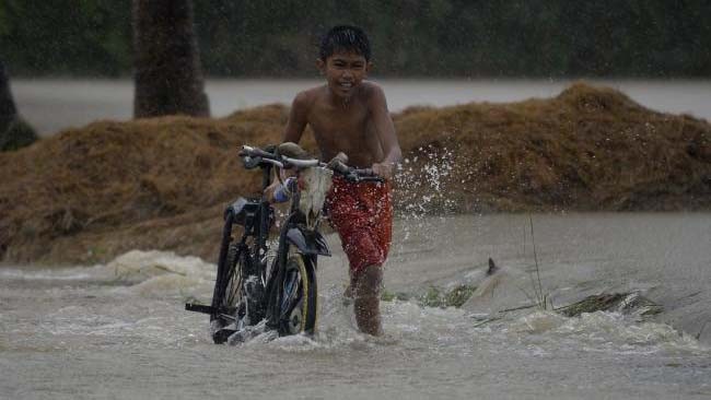Cậu bé dắt xe đạp trên phố ngập nước ở Ineangan, Bambang, Nueva Viscaya