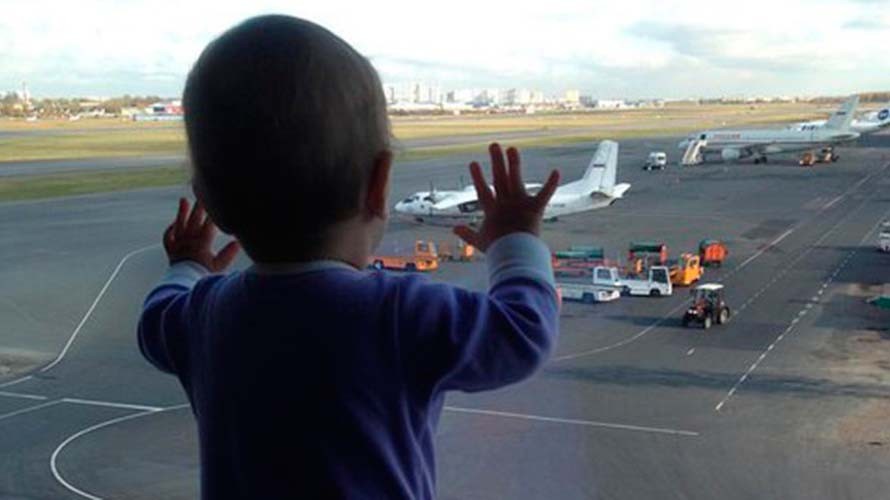 Bé Darina Gromova nhìn những chiếc máy bay qua cửa kính ở sân bay St. Peterburg 