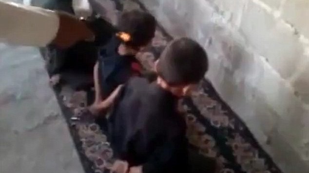 Một cảnh trong đoạn clip cho thấy 4 em nhỏ quỳ gối, tay để sau lưng như những tù nhân