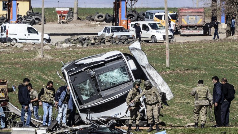 Các binh sỹ đi qua một chiếc xe bị hư hại ở Lice, tỉnh Diyarbakir, Thổ Nhĩ Kỳ sau vụ đánh bom khiến 6 người chết hôm 18/2