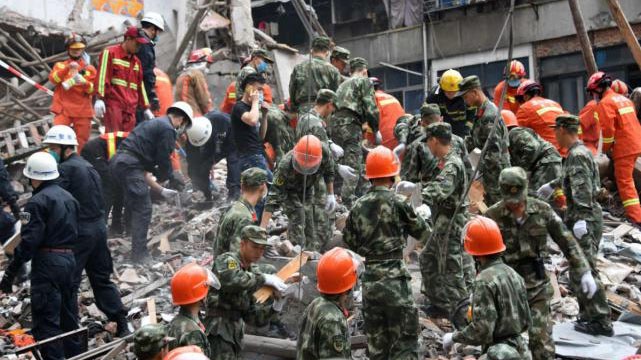 Các nhân viên cứu hộ dùng tay bới đống đổ nát cứu người mắc kẹt trong vụ sập nhà ở Ôn Châu, Trung Quốc.