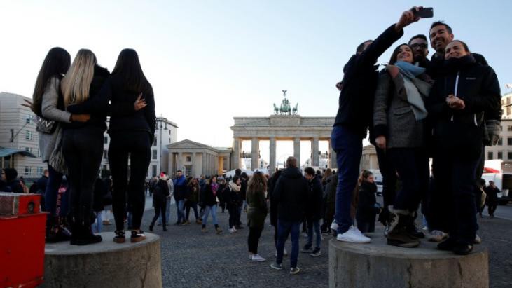 Người dân và du khách đón giao thừa ở Berlin, Đức đứng trên các rào chắn bê tông ở Cổng Brandenburg chụp ảnh.