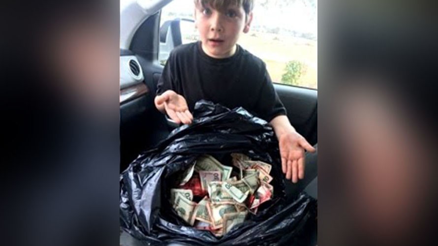 Cậu bé Griffin Steele, 7 tuổi, bên bao tiền lớn cậu tìm thấy gần thùng rác của trạm xăng.