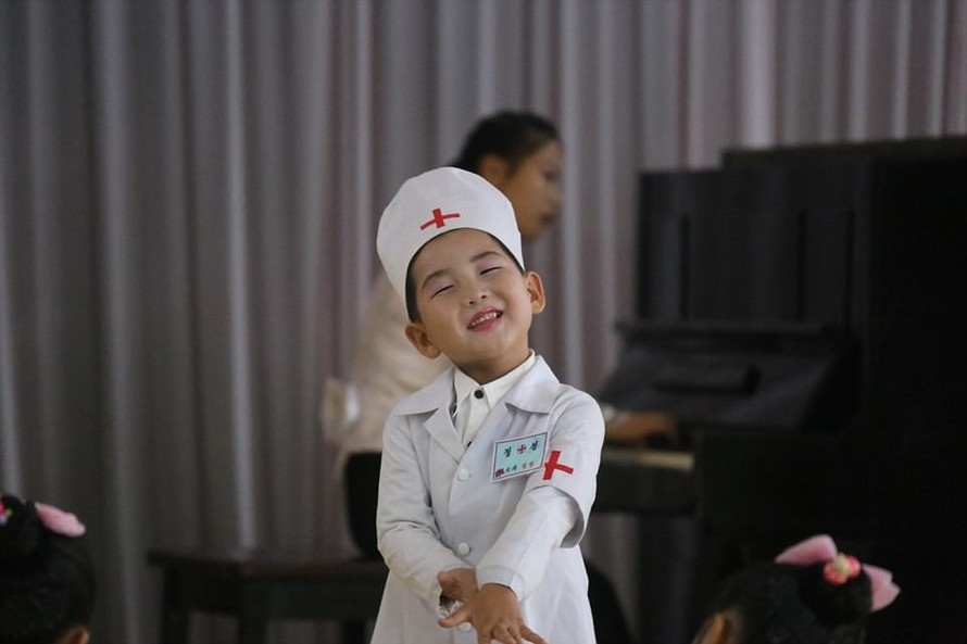 Một bé gái Triều Tiên trong trang phục y tá cười hôn nhiên.