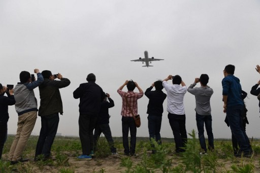 Người dân Trung Quốc thích thú chụp ảnh chiếc máy bay chở khách đầu tiên mang tên Comac C919 do nước này tự sản xuất trong chuyến bay thử nghiệm hôm 5/5 ở sân bay Pudong, Thượng Hải.