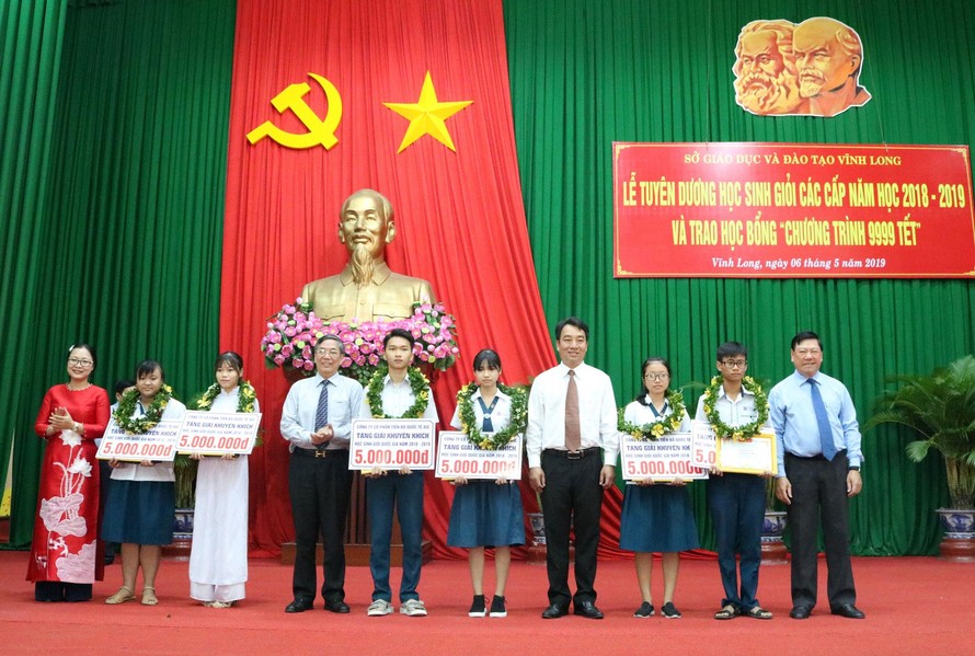 Ông Trần Văn Rón - Bí thư Tỉnh ủy tỉnh Vĩnh Long và ông Lê Vinh - Phó TGĐ AIC Group trao học bổng cho các học sinh .