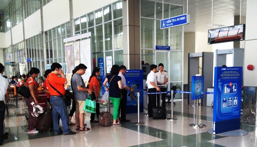 Nhân viên an ninh sân bay kiểm tra giấy tờ tuỳ thân của hành khách tại sân bay Nội Bài