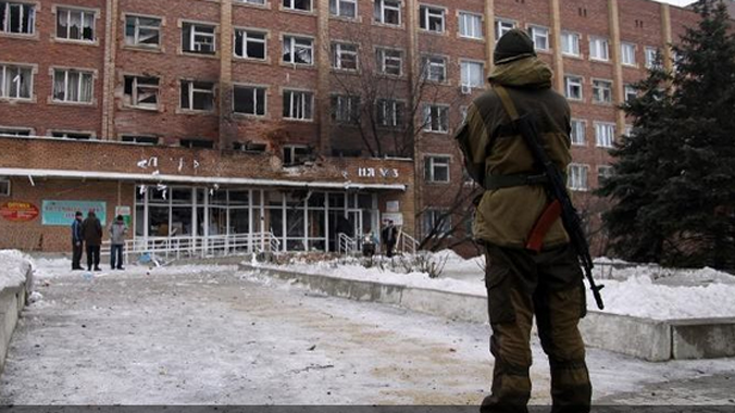 Một lính vũ trang đứng trước bệnh viện bị tàn phá tại Donetsk.