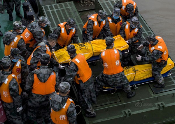 Nhân viên cứu hộ đưa thi thể nạn nhân lên bờ. Ảnh: China Daily
