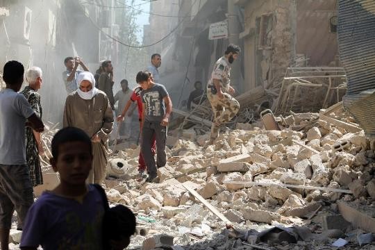 Người dân đi qua đống đổ nát của một tòa nhà bị trúng tên lửa tại Deir Ezzor hồi tháng 9/2013. Ảnh: AFP