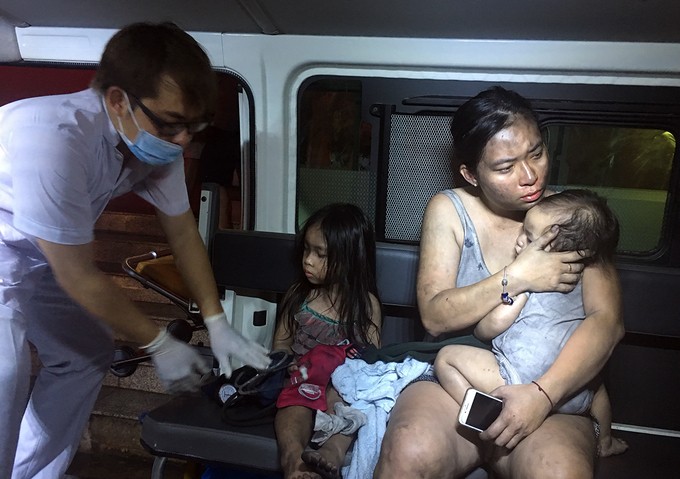 Nhiều phụ nữ cùng con nhỏ bị ám khói đen, nhanh chóng được đưa lên xe cứu thương để được sơ cứu, sau đó chuyển đến bệnh viện. Ảnh: VnExpress