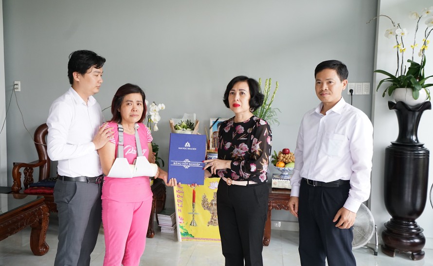Đại diện Ban giám hiệu trường ĐH Hoa Sen trao bang tốt nghiệp cho bà Liên (áo hồng) mẹ của nam sinh Hải Nguyên