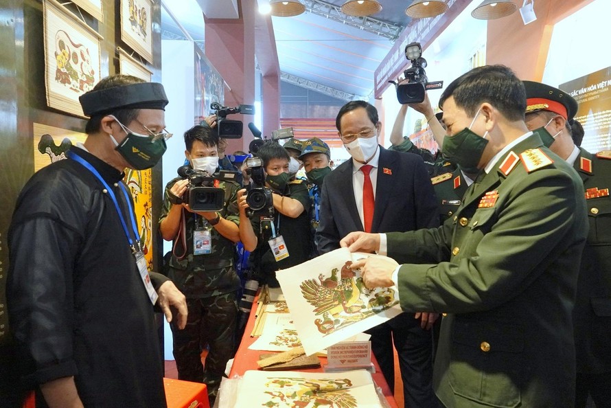 Đại tướng Phan Văn Giang thích thú chia sẻ với Phó Chủ tịch Quốc hội Trần Quang Phương về bức tranh Đông Hồ do tự tay mình làm tại khu vực Không gian văn hóa. Ảnh: Nguyễn Minh