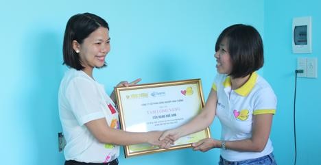 Bà Nguyễn Thị Hồng Ngọc – Giám đốc Kinh Doanh và Tiếp Thị Công ty CPCN Vĩnh Tường trao bảng Tấm lòng vàng cho một đơn vị hỗ trợ xây nhà