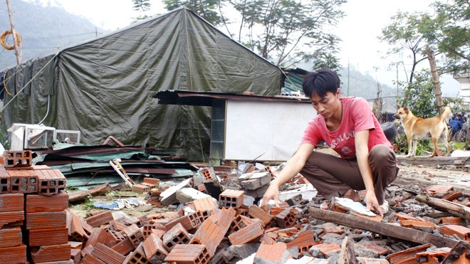 Anh Tạ Hồng Thanh bên ngôi nhà chỉ còn lại là đống đổ nát. Ảnh: Nguyễn Thành