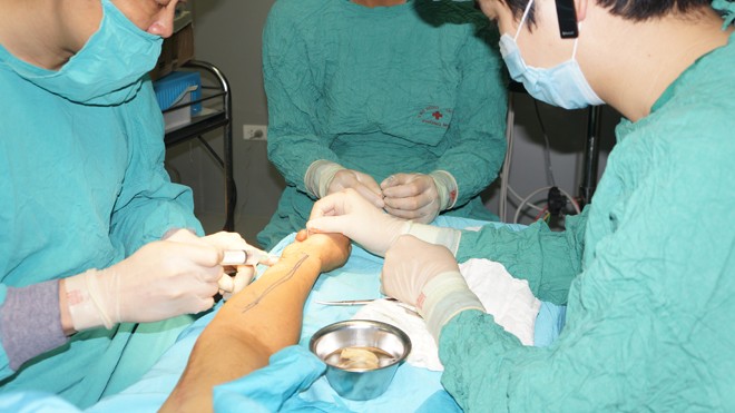 PGS-TS Vũ Quang Vinh (trái) đang phẫu thuật cho bệnh nhân bằng kỹ thuật vi phẫu. Ảnh: P.V