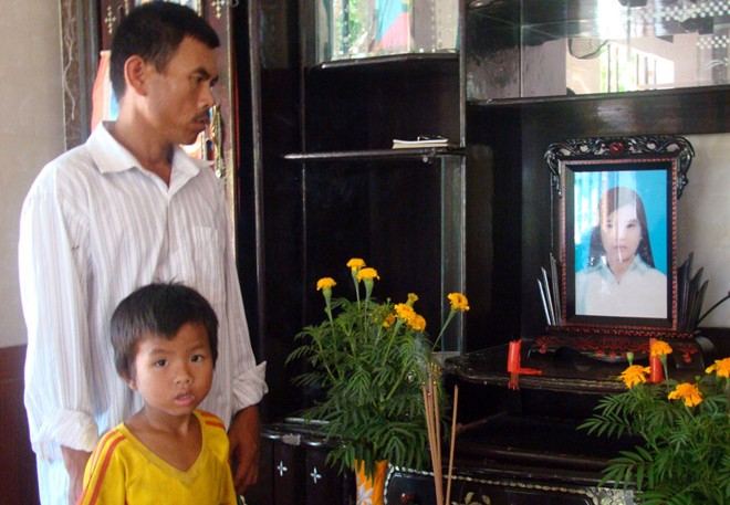 Ông Trần Văn Bình cùng người con trai út bên di ảnh của Trần Thị Yên