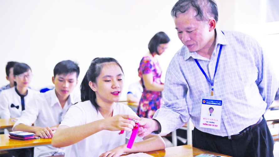 Thứ trưởng Bùi Văn Ga kiểm tra đồng hồ của một thí sinh ĐH Ngoại thương, sau đó chúc học sinh này thi tốt. Ảnh: Như Ý 