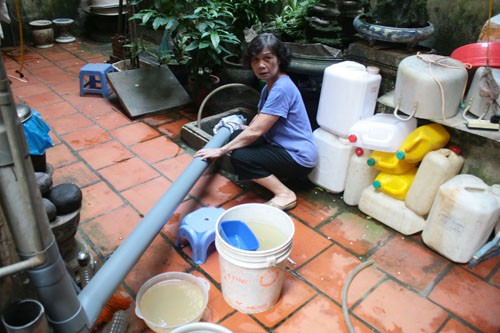 Ngoài việc dùng can đựng nước, bà Bùi Ngọc Châu ở tổ dân phố 35, khu đô thị Định Công (Hoàng Mai) còn nghĩ ra cách nối ống nhựa từ trên tầng thượng xuống bể để hứng nước mưa. Ảnh: Phương Sơn