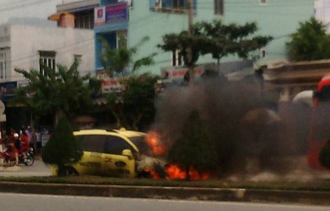 Chiếc xe taxi sau khi bị ép văng qua bên kia đường rồi bốc cháy ngùn ngụt. Ảnh facebook một bạn đọc.