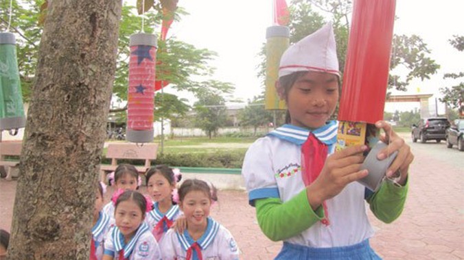 Học sinh trường Trường tiểu học Tân Lộc thích thú “hái” sách báo trên cây để đọc. Ảnh: Nguyên Dũng.
