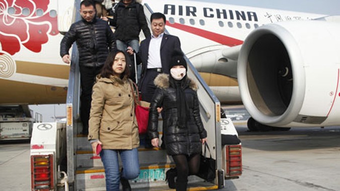 Một nghi phạm tham nhũng (nữ, mặc áo khoác đen, đeo khẩu trang, bên phải) bị cảnh sát áp giải trở về Bắc Kinh sau 10 năm lẩn trốn ở Italia, đối tượng này đã biển thủ 223.700 USD.