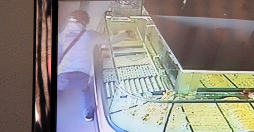 Tên cướp dùng búa đập tủ kính lấy vàng trong 5 giây. Ảnh chụp lại từ màn hình camera.