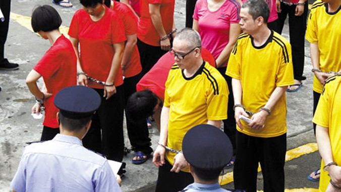 Liang Yaohui (áo vàng đứng trước) và hàng chục đồng phạm tại tòa án Đông Quan. Ảnh: Sina.
