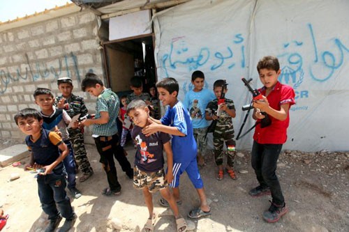 Trẻ em Iraq chơi cùng những khẩu súng đồ chơi phía ngoài một trại tị nạn ở ngoại ô thành phố Arbil hôm 17/7. Ảnh: Reuters.