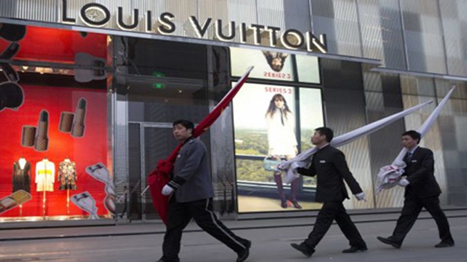 Các nhân viên Trung Quốc đi qua một cửa hiệu Louis Vuitton ở Bắc Kinh. Ảnh: AP.