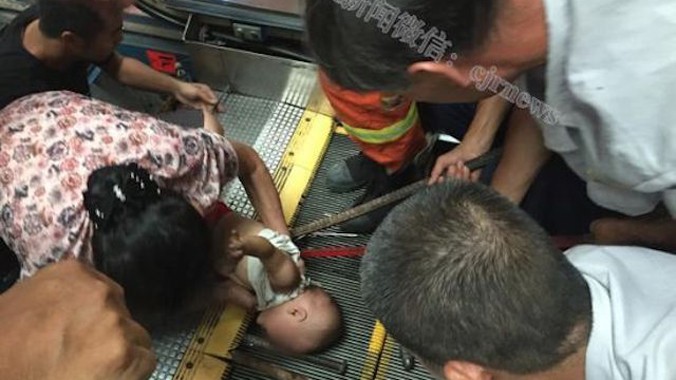 Lính cứu hỏa dùng xà beng để giải cứu em bé mắc kẹt trong thang máy.