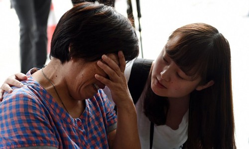 Người thân của hành khách trên chuyến bay MH370 òa khóc ở phía ngoài văn phòng hãng Malaysia Airlines tại Bắc Kinh hôm 6/8. Ảnh: AFP.