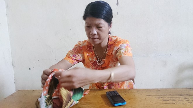 Chị Nguyễn Thị Hán mở lại chiếc khăn đã dùng để bọc gói bật lửa.