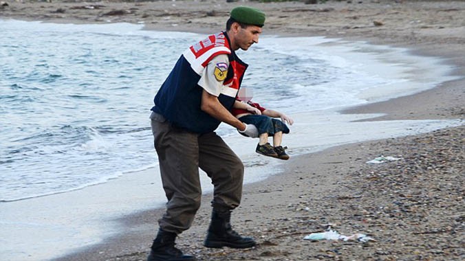 Người lính Thổ Nhĩ Kỳ nhẹ nhàng bế thi thể Aylan khỏi mặt nước. Ảnh: Reuters.