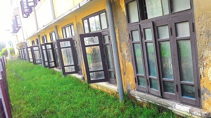 Phần tường bên dưới các ô cửa sổ tầng trệt của Trường THPT Thuận An đã lún gần bằng với mặt sân sau tòa nhà. Đây là thực trạng nguy hiểm chung tại nhiều khối nhà chức năng khác của ngôi trường này. Ảnh: Ngọc Văn.