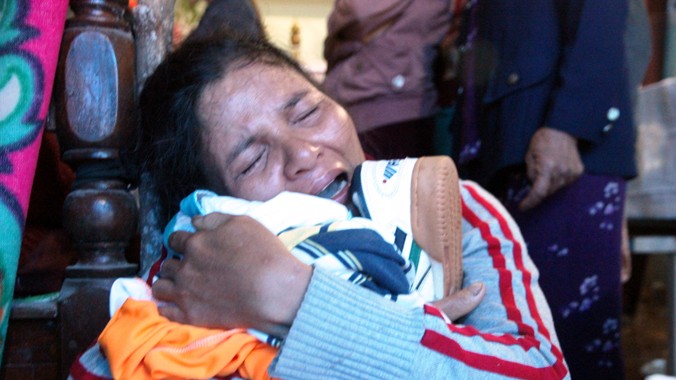 Bà Võ Thị Minh khóc ngất, ôm áo quần của con trai Nguyễn Văn Tín để lại.