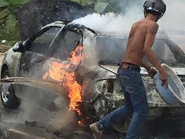 Một người dùng chậu nước hắt vào chiếc xe cháy nhưng ngọn lửa vẫn bùng lên dữ dội, bao trùm cả xe.