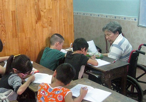 Cô Xinh phải ngồi xe lăn nhưng đã tổ chức lớp dạy học cho trẻ em nghèo suốt 25 năm qua. Ảnh: Hải Dương.
