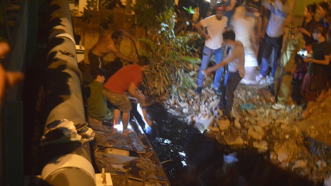 Cảnh sát cùng người dân lùng sục bắt tên trộm dưới kênh nước đen.