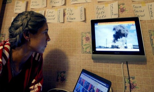 Một cô gái xem bản tin về chiến dịch không kích của Nga tại Syria. Ảnh: kathimerini.gr.