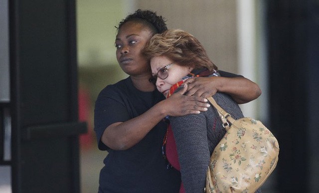 Hai phụ nữ có người thân thiệt mạng trong vụ xả súng an ủi nhau tại một trung tâm cộng đồng. Ảnh: AP.