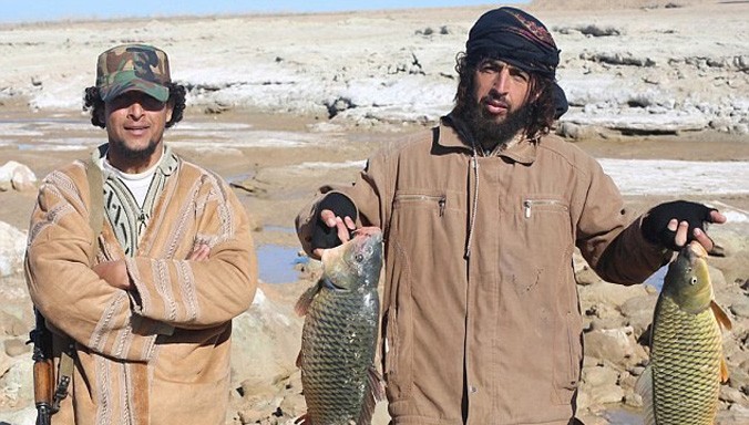 Chiến binh IS khoe chiến lợi phẩm là hai chú cá lớn vừa bắt ở sông Euphrates. Một chiến binh vẫn đeo súng máy tự động bên người.
