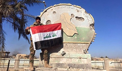Một binh sĩ Iraq giương cờ trên trụ sở hành chính ở Ramadi, Iraq, ngày 28/12.
