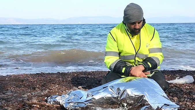 Nhân viên cứu trợ ngồi quỳ gối cạnh thi thể bé gái. Ảnh: "Lighthouse-Refugee Relief on Lesvos".