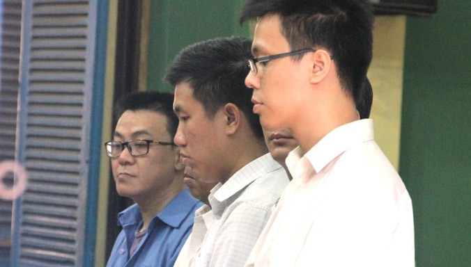 Ngô Thanh Long (áo xanh) và các bị cáo trong ngày đầu của phiên tòa. Ảnh: Tân Châu.
