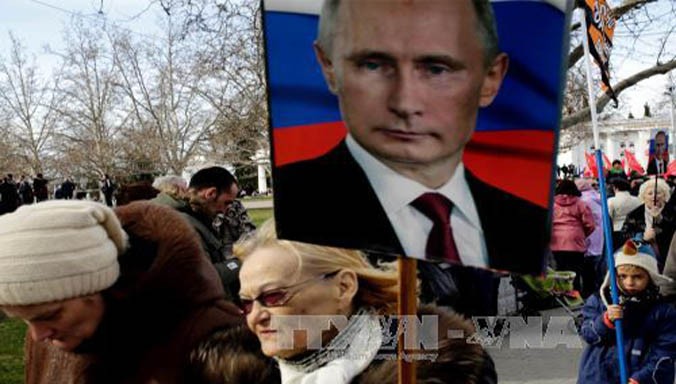 Người dân giơ cao ảnh chân dung Tổng thống Nga tại cuộc tuần hành nhân kỷ niệm Ngày Vệ quốc ở Sevastopol thuộc bán đảo Crimea ngày 23/2. Ảnh: AFP/TTXVN.