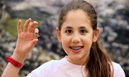 Neshama Spielman và chiếc bùa hộ mạng hình mặt dây chuyền mà cô bé tìm thấy trong công viên quốc gia của Jerusalem. Ảnh: CBC.