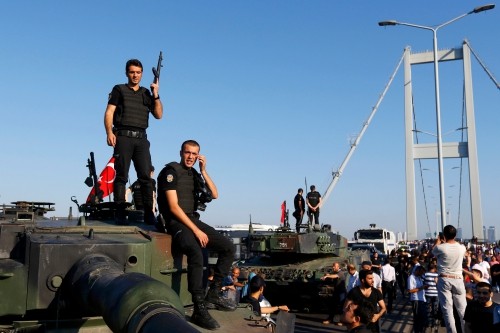 Cảnh sát đứng trên nóc xe bọc thép sau khi binh lính tham gia đảo chính đầu hàng trên cầu Bosphorus ở Istanbul. Ảnh: Reuters.