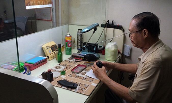 Ông Nguyễn Văn Tần cặm cụi trong góc nhỏ tiệm ảnh mà mình xin ngồi nhờ.