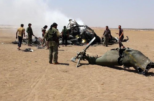 Các phiến quân Syria đứng trước xác chiếc trực thăng Nga bị bắn rơi ở tỉnh Idlib hôm 1/8. Ảnh: AFP.